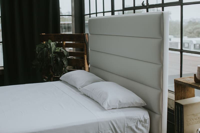Pillows against the horizontal channel headboard in white vegan leather