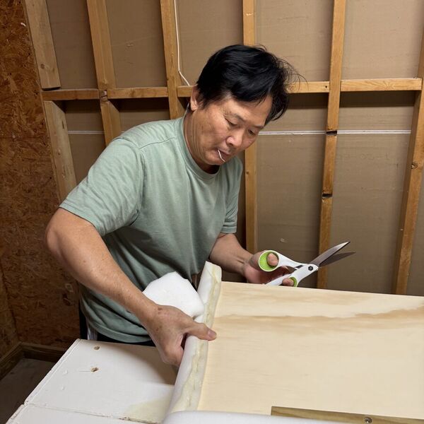 Our craftsman cutting upholstery fabric with shears on the workbench